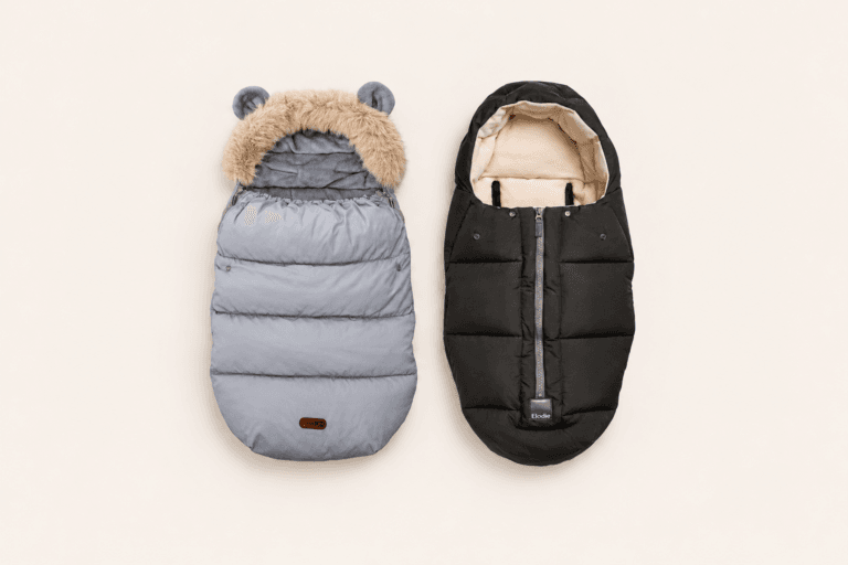 Siva FreeON Arctic i crna Elodie Comfort zimska vreća za kolica, prikazane jedna uz drugu na krem pozadini.